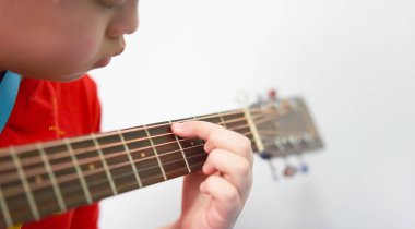 Eller ve parmaklar gitar çalan akorları kavrıyor. Çocuk gitar tellerini çalan ele dikkatle baktı.