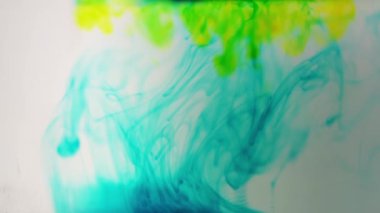 mavi ve sarı renkli boya mürekkep suyu yavaş çekimde düşer.