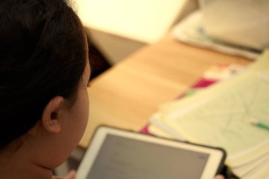 Çocuk internetten internet dersi öğreniyor. Okul öğretmeninden tabletle ders alıyor ve Coronavirus covid 19 karantina konsepti üzerine masa başında ödev yapıyor.