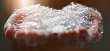 Avuçlarında ışık kabarcıkları tutan el.