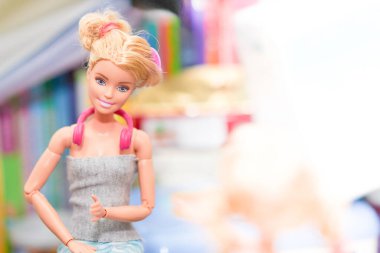 Kız çocuklar süs oyuncağıyla kostüm içinde Barbie bebek oynuyorlar.