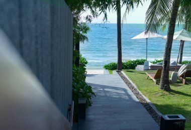 Otelin ve gökyüzünün önünde kumsala yürü.