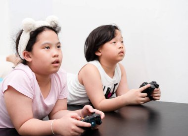 Asyalı çocuklar evde kontrolör tarafından video oyunu oynuyorlar