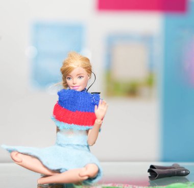 Aksesuarları bulanık arka planda olan oyuncak bebek mindere otur.