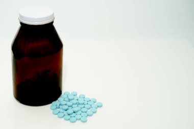 Mavi haplar, yerde, şişenin yanında, beyaz, fotokopi alanı olan.