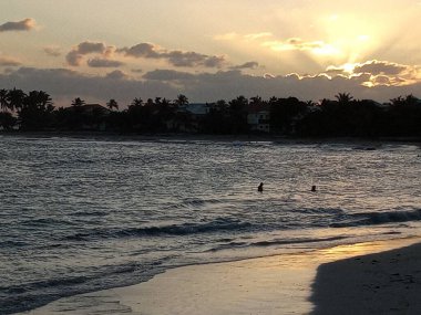 Güneş denizden yansıyan bulutların ardında batar.