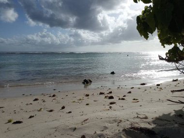 Kumsalın arkasında, deniz ve bulutlu gökyüzü