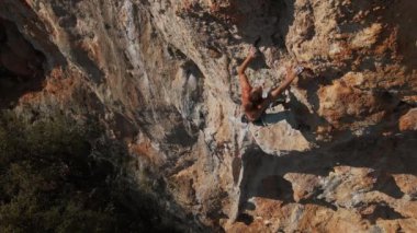 Güçlü, kaslı kaya tırmanışçısının havadan yavaş çekimleri dikey uçuruma tırmanıyor ve sıkı çaba sarf ediyor, sıkı tutunuyor. Çıplak gövde sporcusu eğitimi. Türkiye 'de kaya tırmanışı, Geyikbayiri