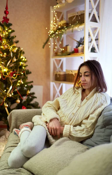 Alone sad woman dont like Christmas time, tired and unhappy at decorated festive living room