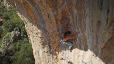 top view young strong athletic man rock climber climbs on overhanging cliff by challenging route. male climbing very hard route making long movement. extreme sport, rock climbing outdoors, training