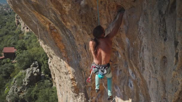 年轻的攀岩运动员 长发爬上悬崖峭壁 男性爬得很辛苦 步履艰难 极限运动 户外攀岩 训练时刻 — 图库视频影像