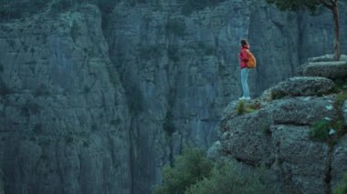 Dağların tepesinde kırmızı ceketli bir yürüyüşçü kadın. Güzel manzaranın tadını çıkarıyor. Saç kesiyor, Kanyon Milli Parkı 'nda yürüyüş yapıyor. Grayhound Tazi Kanyonu Türkiye 'nin ünlü turistik mekanı.