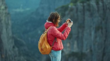 Yürüyüşçü kız akıllı telefonuyla Tazi Kanyon manzarasının fotograflarını ya da videosunu çekiyor. Uçurumun tepesinde mutlu bir kadın dağ manzarasının keyfini sürüyor, Türkiye 'nin ünlü turistik mekanında yürüyüş yapıyor.