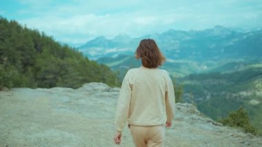 Gülümseyen kız dağların arkasında yürüyor ve onu takip etmek için çağırıyor. Türkiye 'de doğa ve doğanın güzelliğinin tadını çıkaran kadın gezgin. Tatil konseptimi izleyin.