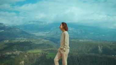 Yavaş çekim Genç Kadın çarpıcı bir dağ sırasının arka planında yürüyor. Dürüst kız turist doğa ve seyahat özgürlüğünün tadını çıkarıyor..