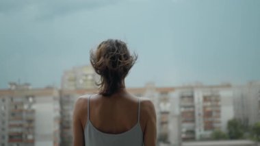 Arka planda, gecelikle balkonda duran genç bir kadın, arka planda dramatik bir gökyüzü. Depresif sahne, yüksekten atlamayı düşünen bir kız. Depresyon ve akıl hastalığı, intihar düşünceleri.
