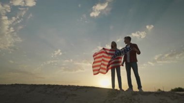 Mutlu vatansever çiftin 4 Temmuz kutlamalarını kırsal kesimde, günbatımında ulusal bayrak çekerek 4 km yavaş çekimleri. 4 Temmuz. ABD 'nin bağımsızlık gününü Amerikan bayrağıyla kutluyoruz.