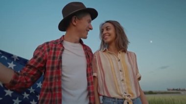 Mutlu vatansever çiftin 4 Temmuz kutlamalarını kırsal kesimde, günbatımında ulusal bayrak çekerek 4 km yavaş çekimleri. 4 Temmuz. ABD 'nin bağımsızlık gününü Amerikan bayrağıyla kutluyoruz.