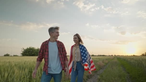 7月4日を祝う幸せな愛国的なカップルの4Kスローモーション日没時に農村部のランドマークで国旗と 7月4日 アメリカ独立記念日アメリカ国旗で祝う — ストック動画