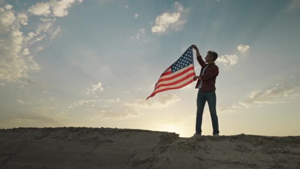 夕焼け空を背景にアメリカ国旗が流れる男のシルエット 7月4日のお祝い屋外 スローモーション農村シーン — ストック動画