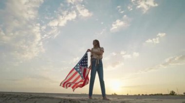 woman silhouette with flowing USA flag against sunset sky. 4th of july celebration outdoor, slow motion rural scene