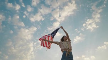 woman silhouette with flowing USA flag against sunset sky. 4th of july celebration outdoor, slow motion rural scene