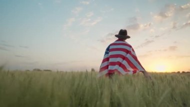 man walking with American flag. 4 of July, Independence day celebration. Slow-motion wide angle ground view camera following. View from back. Patriotic holiday, democracy and veteran respect conept