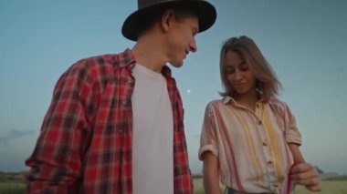 4k slow motion of happy patriotic couple celebrating fourth of july with national flag in rural lardmark at sunset. Federal holiday. 4 July Independence day celebrating with national American flag