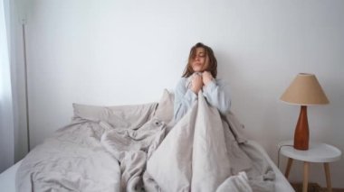young woman lies alone on bed at home, cold and sick. illness, cold, virus, doctors call at home, consultation with a doctor by phone