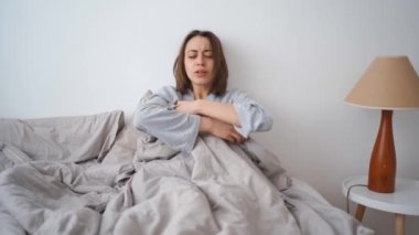 young woman lies alone on bed at home, cold and sick. illness, cold, virus, doctors call at home, consultation with a doctor by phone