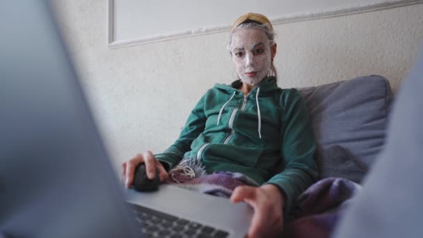 Young Woman Handmade Cosmetic Mask Face Sits Home Couch Laptop — Video