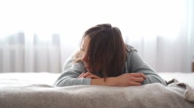happy joyful smiling woman lying on bed in bedroom and playing with her cute funny welsh corgi dog. friendship with pets, games together and leisure. domestic animals in peoples life