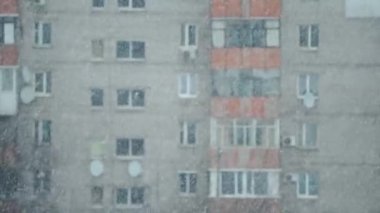 abstract winter scene with flying snowflakes on background of houses at clear winter day
