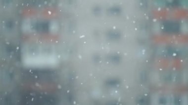abstract winter scene with flying snowflakes on background of houses at clear winter day