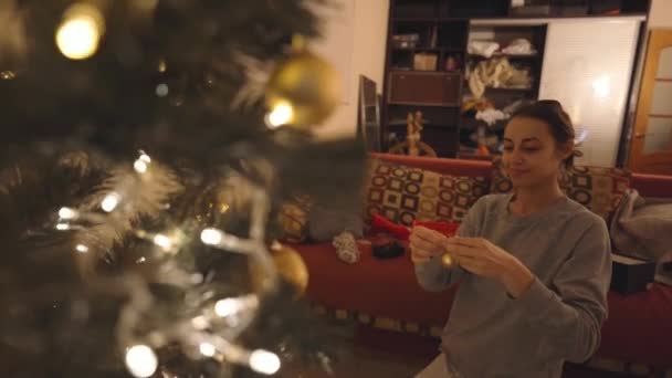 Beautiful Smiling Woman Decorates Christmas Tree Home Bulbs Making Nice — Vídeos de Stock