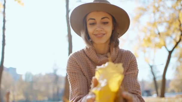 스웨터를 모자를 아름다운 미소를 여성의 아름다운 초상화 나뭇잎을 장난기있게 카메라를 — 비디오