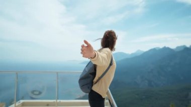 Yandan bakan özgür kadın kollarını açmış gülüyor ve dağ manzarasından zevk alıyor, yaz tatili