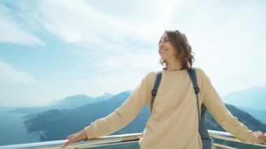 Olumlu gülümseyen beyaz kadın turist dağların arasından nefes kesici manzaranın tadını çıkarıyor. Macera ve seyahat keşfi