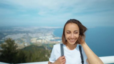 Sırt çantalı neşeli turist kadın dağın tepesinde duruyor, Tunektepe Teleferik, Antalya manzarasının tadını çıkarıyor.
