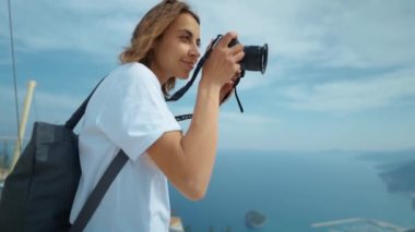 beautiful woman travel blogger taking photo or video on professional camera, standing at viewpoint among mountains and blue sky. viewpoint of Tunektepe Teleferik, Antalya