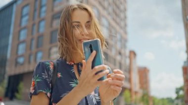slow motion attractive happy caucasian woman with beautiful smile laughing female using mobile phone while standing on city street and talking someone. woman have dating outdoors