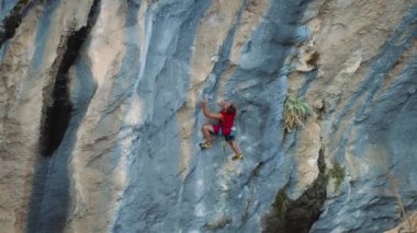 Güzel mavi kayalık duvar, çarpıcı ve renkli erozyonal su oluşumu. Sporcu adam, ağır çekimde 4k 'ye tırmanıyor.