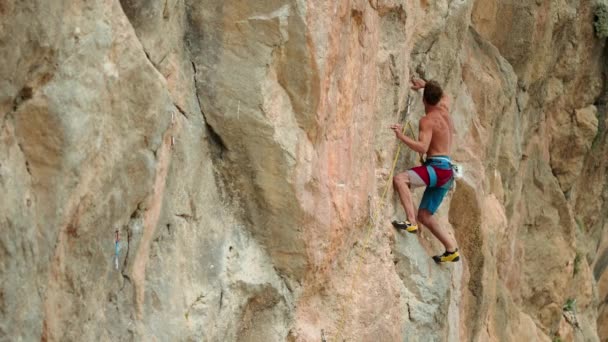 强壮英俊的男人 肌肉发达的身体爬上垂直的悬崖 线条优美 石质细腻 攀登者在户外有山有水 — 图库视频影像