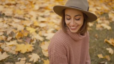 slow motion close up charming woman walks in bright autumn park with yellow foliage. stylish vintage woman in park at warm fall day holds wicker basket with orange pumpkins
