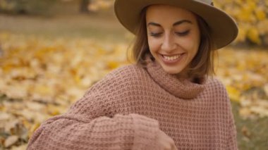 slow motion close up charming woman walks in bright autumn park with yellow foliage. stylish vintage woman in park at warm fall day holds wicker basket with orange pumpkins