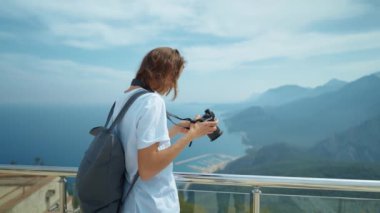 attractive woman hipster travel blogger takes photo on professional camera, viewpoint among mountains and blue sky, cableway destination. viewpoint of Tunektepe Teleferik, Antalya, Turkey