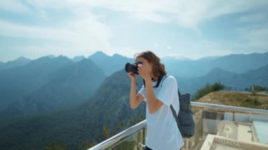 Çekici kadın hipster seyahat blogcusu profesyonel kamerada fotoğraf çekiyor, dağların ve mavi gökyüzünün bakış açısı, kablo yolu durağı. Tunektepe Teleferik 'in bakış açısı, Antalya, Türkiye
