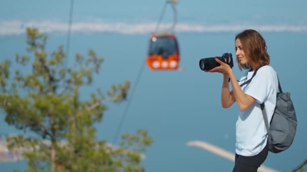 漂亮的女性旅行博主 在专业相机上拍照或录像 在群山和蓝天之间的观点 背景上的电缆 土耳其安塔利亚Tunektepe Teleferik的观点 — 图库视频影像