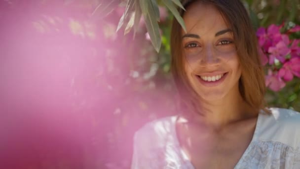 Güzel Esmer Esmer Pembe Çiçeklere Bakıp Büyüleyici Bir Gülümsemeyle Kameraya — Stok video