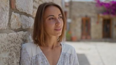 Ağır çekimde gülümseyen, çiçekli, beyaz elbiseli güzel bir kadın, şehrin eski bir bölgesinde yürüyüş yapıyor ve Datcha, Türkiye 'de tatilin tadını çıkarıyor..